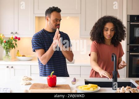 Ein Paar Zu Hause Mit Einem Mann Mit Down-Syndrom Und Einer Frau, Die Zusammen In Der Küche Essen Zubereitet Stockfoto