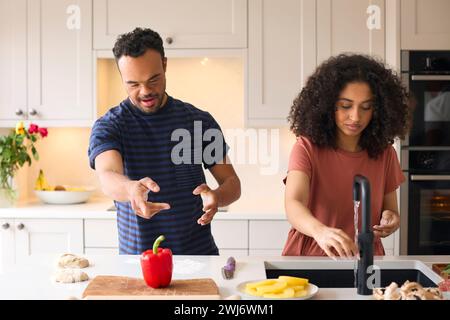 Ein Paar Zu Hause Mit Einem Mann Mit Down-Syndrom Und Einer Frau, Die Zusammen In Der Küche Essen Zubereitet Stockfoto