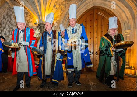 London, Großbritannien. Februar 2024. Die jährlichen Inter-Livery Pancake-Rennen in der Regel Guildhall Yard am Faschingsdienstag, aber dieses Jahr wurde wegen des regnerischen Wetters in die Krypta verlegt. Teams, die entweder schicke Kleidung oder volle Insignien tragen, rennen um den Guildhall Yard herum und werfen ihre Pfannkuchen. Der Wettbewerb findet seit über 15 Jahren jährlich statt, und die Erlöse fließen an wohltätige Zwecke. Guy Bell/Alamy Live News Stockfoto