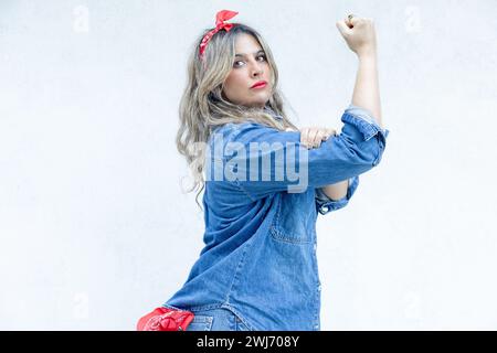 Mit einem entschlossenen Blick und einer kräftigen Faust steht eine Frau in einem Denim-Outfit als modernes Symbol für die Stärke und Ermächtigung, die es ausmacht Stockfoto