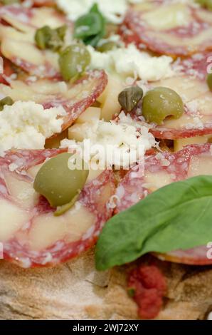 Traditionelle Pizza mit Peperoni-Wurst, Oliven und Mozzarella, abstrakter Essenshintergrund Stockfoto