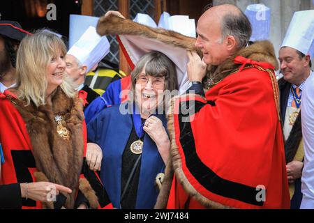 London, UK, 13. Februar 2024. Mitglieder der Lackierung, Richter und Stadträte und Frauen der City of London schützen sich vor dem starken Regen, der das Rennen abbricht. Beim jährlichen Inter Livery Pancake Race treten normalerweise Teams von Livery-Mitgliedern der Worshipful-Unternehmen der City of London an den Fun Pancake-Rennen am Faschingsdienstag im Guildhall Yard an, entweder in schickem Kleid oder voller Insignien. Wegen anhaltendem Regen mussten die eigentlichen Rennen kurzfristig abgesagt werden, aber Teilnehmer und Richter genießen einen Fotoruf, bevor sie in die Gildenhalle gehen, um Essen und Kostüme zu beurteilen. Stockfoto