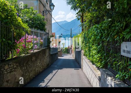 Enge Straße in Bellagio, Italien, mit einem wunderschönen Blick auf den Comer See und die Berge an einem schönen Sommertag. Stockfoto