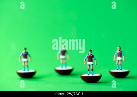 Eine Gruppe von Subbuteo Miniaturfiguren, die in den Farben der Aston Villa FC Heimmannschaft gemalt sind: Dunkelrote und blaue Hemden, weiße Shorts und dunkelrote und blaue Socken Stockfoto