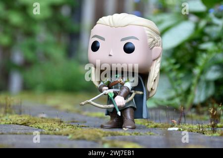 Funko Pop Actionfigur von Elf Legolas aus dem Fantasy-Film der Herr der Ringe. Krieger, der Bogen und Pfeil hält. Grüne Blätter, Moos, Steinweg. Stockfoto