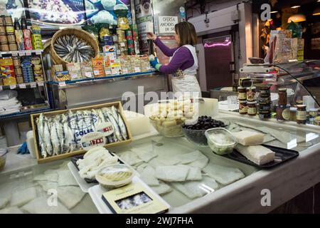 Kabeljau- und Blaufischstand mit seinem Besitzer, der die Waren auf dem alten zentralen Markt von Abaceria in Barcelona arrangiert Stockfoto