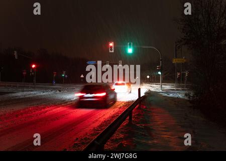Zwei Autos, die nachts in gießen bei einem Schneesturm über die Kreuzung fahren Stockfoto
