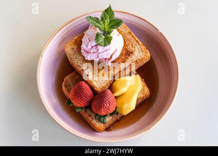 Toast mit Erdbeeren, Mango und Eis mit Ahornsirup in einer Schüssel Stockfoto