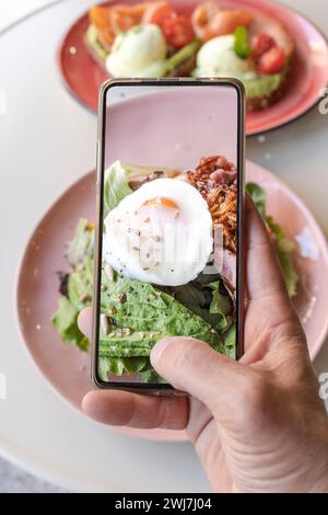 Smartphone-Fotos von vegetarischem Mittagessen oder Abendessen. Die Hände eines Mannes machen Fotos von Lebensmitteln in modernem Stil für soziale Netzwerke oder Blogs. Stockfoto