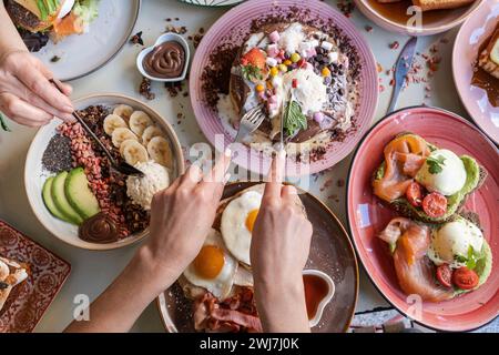 Das Frühstück wird mit verschiedenen Gerichten wie Eiern, Speck, Pfannkuchen und Obst auf einem farbenfrohen Tisch serviert Stockfoto