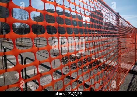 Gut sichtbares Netz, Arbeiten auf einer Baustelle, Zaun einer Baustelle mit gut sichtbaren orangefarbenen Elementen. Sicherheit Stockfoto