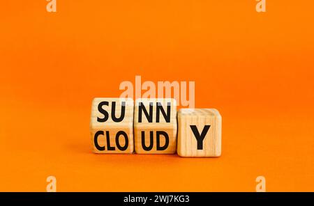 Sonniges oder bewölktes Symbol. Konzeptwort sonnig oder bewölkt auf Holzwürfeln. Schöner oranger Tisch mit orangefarbenem Hintergrund. Business Lifestyle und sonnig oder bewölkt Stockfoto
