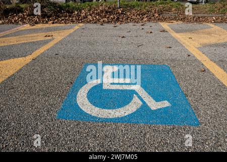 Straßensymbol für Behindertenparkplätze, weißes Symbol auf einem blauen Feld gemäß der europäischen Straßenverkehrsordnung. Platz für Fahrzeuge mit Behinderten an Bord Stockfoto