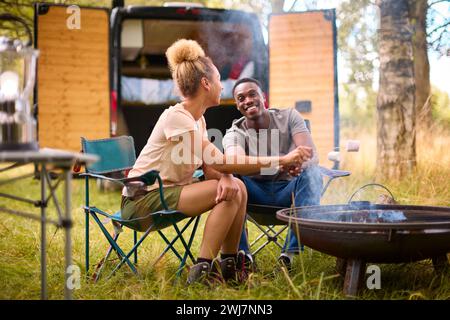 Paare Camping auf dem Land mit Wohnmobil, das Marshmallows im Freien auf Feuer toast Stockfoto