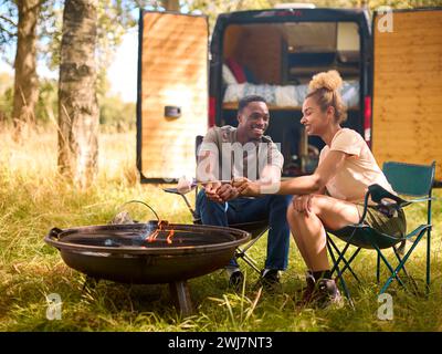 Paare Camping auf dem Land mit Wohnmobil, das Marshmallows im Freien auf Feuer toast Stockfoto