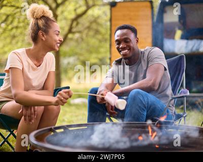 Paare Camping auf dem Land mit Wohnmobil, das Marshmallows im Freien auf Feuer toast Stockfoto