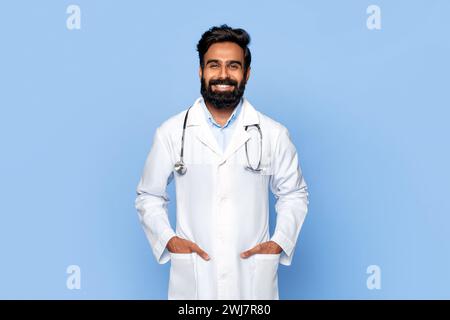 Porträt eines selbstbewussten männlichen Arztes mit Händen in Taschen auf blauem Hintergrund Stockfoto