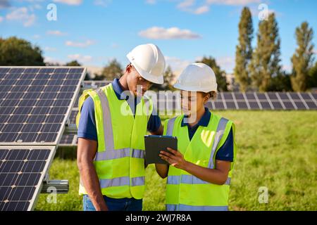 Männliche Und Weibliche Ingenieure Mit Digitalem Tablet, Die Solarpaneele Zur Erzeugung Erneuerbarer Energien Inspizieren Stockfoto