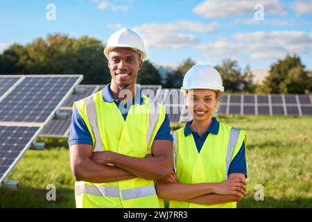 Porträt Lächelnder Männlicher Und Weiblicher Ingenieure Bei Der Inspektion Von Solarpaneelen, Die Erneuerbare Energien Erzeugen Stockfoto