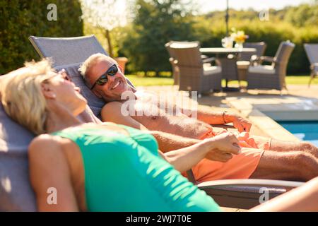 Seniorenpaar Im Urlaub In Badekleidung, Entspannend Am Hotelpool Stockfoto