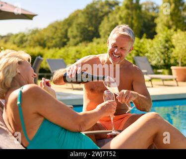 Seniorenpaar Im Urlaub In Badekostümen Und Mit Champagner Am Hotelpool Stockfoto