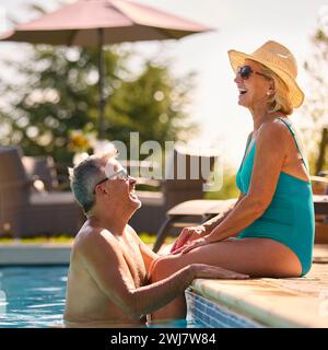 Liebevolles Seniorenpaar Im Urlaub In Badekleidung, Entspannend Am Hotel Swimmingpool Stockfoto