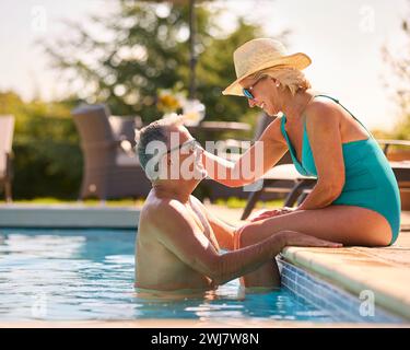 Liebevolles Seniorenpaar Im Urlaub In Badekleidung, Entspannend Am Hotel Swimmingpool Stockfoto