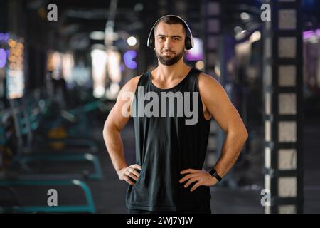 Porträt Eines Gutaussehenden Jungen Muskulösen Mannes In Kopfhörern, Der Im Fitnessstudio Posiert Stockfoto