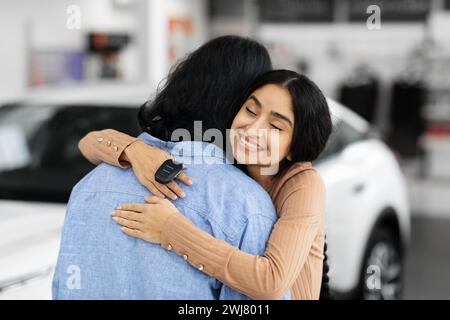 Glückliche junge indianerin mit Autoschlüssel, der ihren Mann umarmt Stockfoto