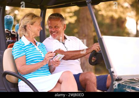 Senior Pärchen Sitzen Im Buggy Auf Dem Golfplatz Und Markieren Gemeinsam Die Punktekarte Stockfoto