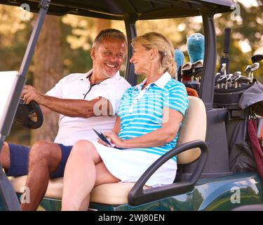 Senior Pärchen Sitzen Im Buggy Auf Dem Golfplatz Und Markieren Gemeinsam Die Punktekarte Stockfoto