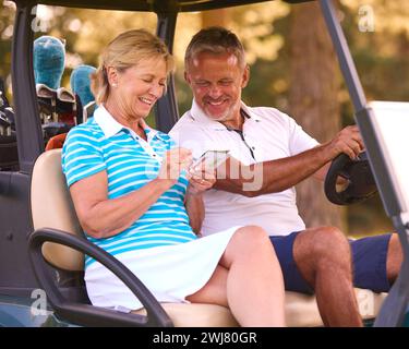 Senior Pärchen Sitzen Im Buggy Auf Dem Golfplatz Und Markieren Gemeinsam Die Punktekarte Stockfoto