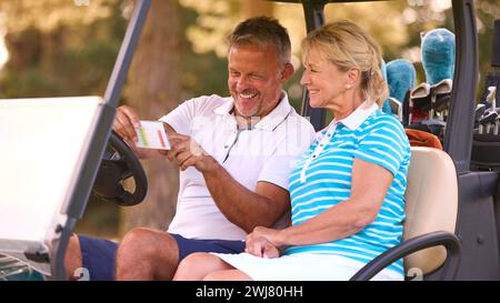 Senior Pärchen Sitzen Im Buggy Auf Dem Golfplatz Und Markieren Gemeinsam Die Punktekarte Stockfoto