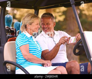 Senior Pärchen Sitzen Im Buggy Auf Dem Golfplatz Und Markieren Gemeinsam Die Punktekarte Stockfoto