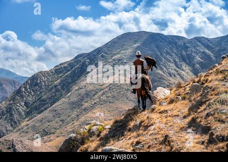 Traditioneller kirgisischer Adlerjäger in den Bergen auf der Jagd zu Pferd, in der Nähe von Kirgisil-Suu, Kirgisistan Stockfoto