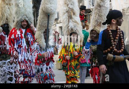 Sinj, Kroatien. Februar 2024. Menschen, die Schafvlies auf dem Kopf tragen, nehmen am 13. Februar 2024 an der Karnevalsparade der Region Cetina in Sinj, Kroatien, Teil. Didi aus Kamesnica tragen auf ihren Köpfen Schafvliese, bis zu 1,5 Meter hoch und Glocken um die Taille. Sie tragen alte Kleider, die mit bunten Fransen genäht sind. Sie symbolisieren den rituellen Kampf der guten Geister gegen den Winter, indem sie ihn verjagen, indem sie Lärm machen und auf und ab springen. Foto: Ivana Ivanovic/PIXSELL Credit: Pixsell/Alamy Live News Stockfoto