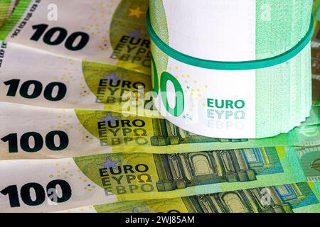 Eine Rolle von hundert Euro-Banknoten mit einem grünen Gummiband auf einem Hintergrund von 100 Euro-Banknoten Stockfoto