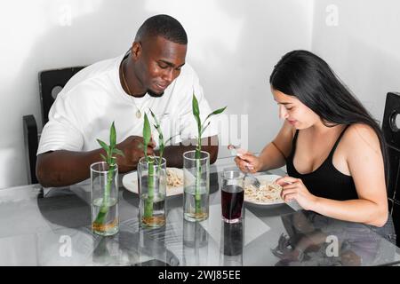 Ein junges lateinisches multiethnisches Paar, das im Speisesaal Nudeln isst und sich unterhält Stockfoto