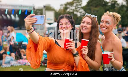 Drei Weibliche Freunde Mit Glitzer Posieren Für Selfie Beim Summer Music Festival Und Halten Drinks Stockfoto
