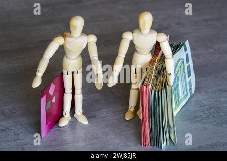 Zwei menschliche Holzfiguren symbolisieren das Konzept der Verwendung von Bargeld oder Zahlungskarten, Bargeld oder Kartenwahl Stockfoto