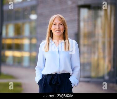 Porträt Einer Lächelnden Geschäftsfrau, Die Vor Dem Modernen Bürogebäude Steht Stockfoto