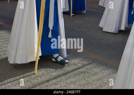 Detail der Füße einiger Nazarener mit blauen Sandalen und weißer Tunika bei einer Palmensonntagsprozession in Spanien Stockfoto