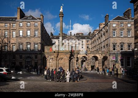 Touristen treffen sich auf einem Spaziergang am Mercat Cross vor den City Chambers auf der High Street in Edinburghs Altstadt. Stockfoto