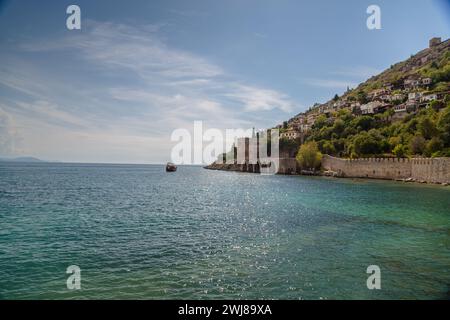 Wunderschöner Sandstrand und weiche türkisfarbene mediterrane Meereswelle - Landschaft der alten Werft in der Nähe des Kizil Kule Turms - Alanya Halbinsel, Türkei Stockfoto