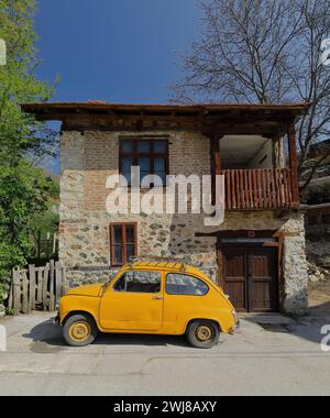 338 klassisches Zastava Z750 LE von 1980, orange-gelb gefärbtes, sogenanntes Fikjo-Auto, parkt vor einem Volkshaus. Vevchani-Nordmazedonien. Stockfoto