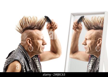 Mann kämmt seine mohawk-Frisur mit einem Pinsel vor einem Spiegel isoliert auf weißem Hintergrund Stockfoto