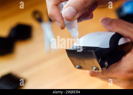 Friseur, der Öl in seine Haarschneidemaschine mit einer kleinen Flasche eingießt. Stockfoto