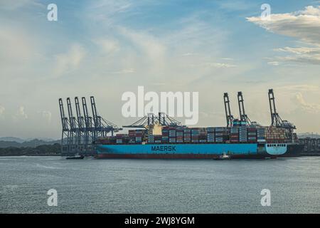 Panamakanal, Panama - 24. Juli 2023: Nahaufnahme, Maersk Edmonton Containerschiff im Hafen von Balboa, Kraniche entlang des Kais unter blauer Morgenwolke Stockfoto