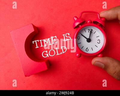 Die Draufsicht der Uhr mit DER TEXTZEIT IST GOLD auf rotem Hintergrund. Stockfoto