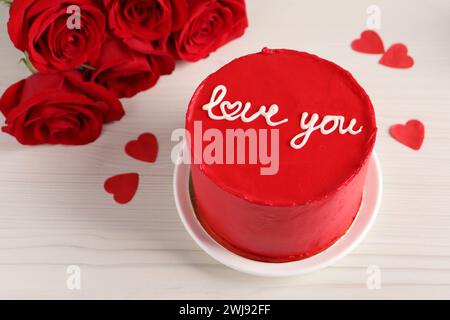 Bento Kuchen mit Text Love You, Rosen und Papierherzen auf weißem Holztisch, Platz für Text. St. Valentinstag-Überraschung Stockfoto